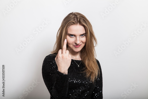 portrait of cute blond teenager making insult middle finger gesture