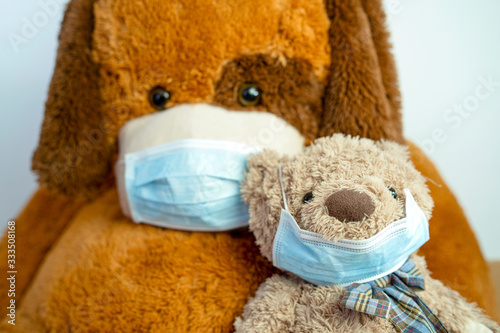 Two brown teddy bears - small and big - wearing protective blue masks