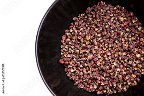 Scented Sichuan pepper in  the black bowl on the white table isolated image. Sichuan pepper or Chinese pepper or Timur or Nepali pepper is very popular in cuisines of Tibet, Bhutan, Nepal, Thailand. photo