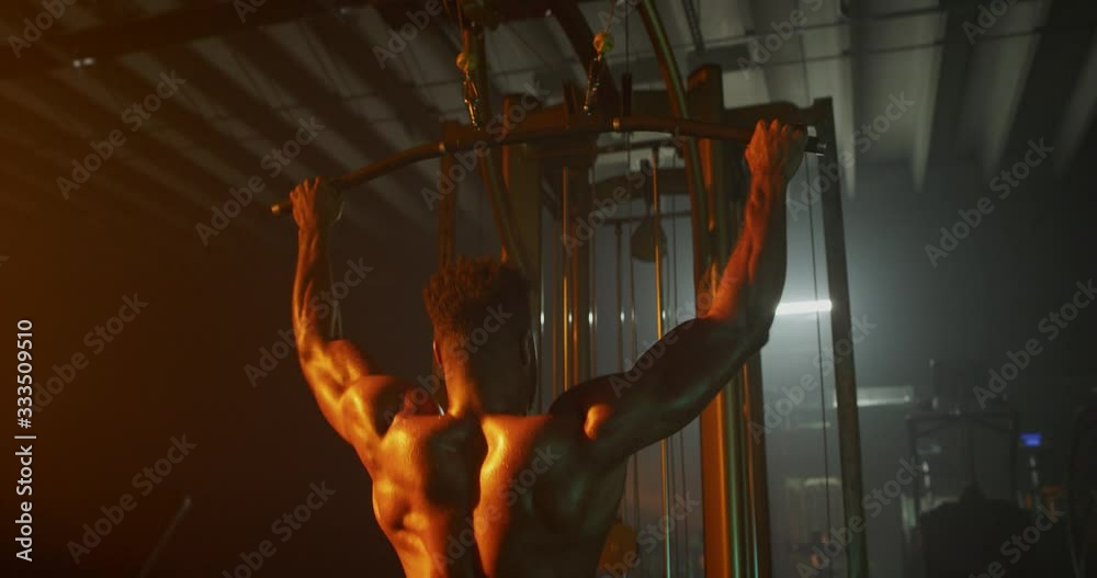Man working out back muscles in dark gymMan working out in dark gym