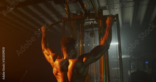 Man working out back muscles in dark gymMan working out in dark gym