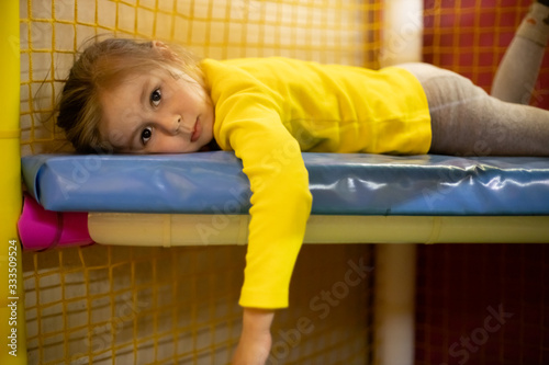 Little tired girl in a children playroom