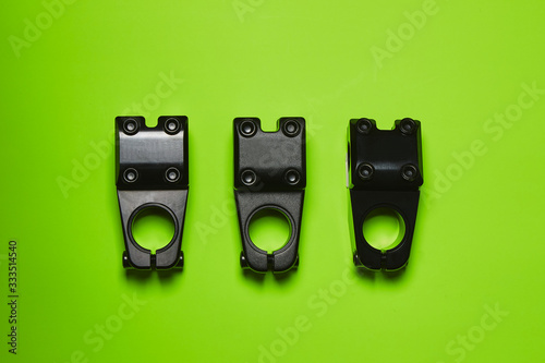 Three stem for bmx steering lie on a bright green background. Parts for bicycles. Extreme sports.