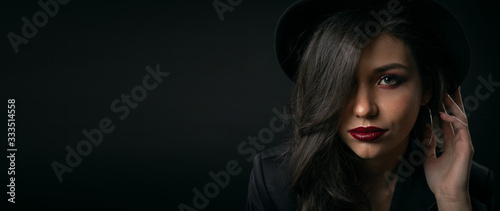 Headshot of serious charming young lady touching hat hiding half face behind hair, copyspace