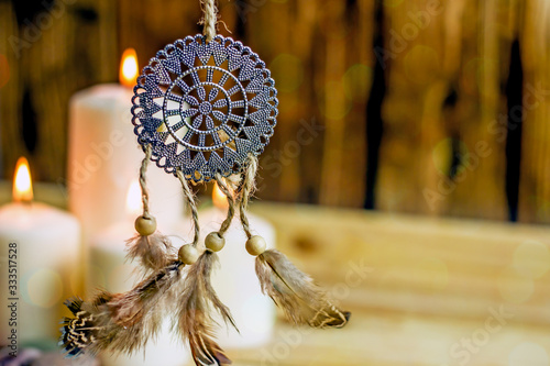 Dreamcatcher amulet feng shui. Dream catcher from metal and farts against the background of burning candles. Background concept about magic, sorcery, esotericism, feng shui symbol