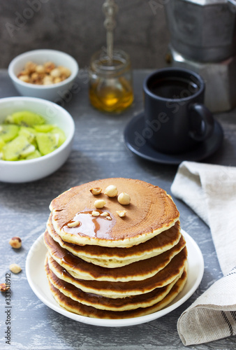 Vegetarian breakfast of pancakes, coffee, honey, nuts and fruits.