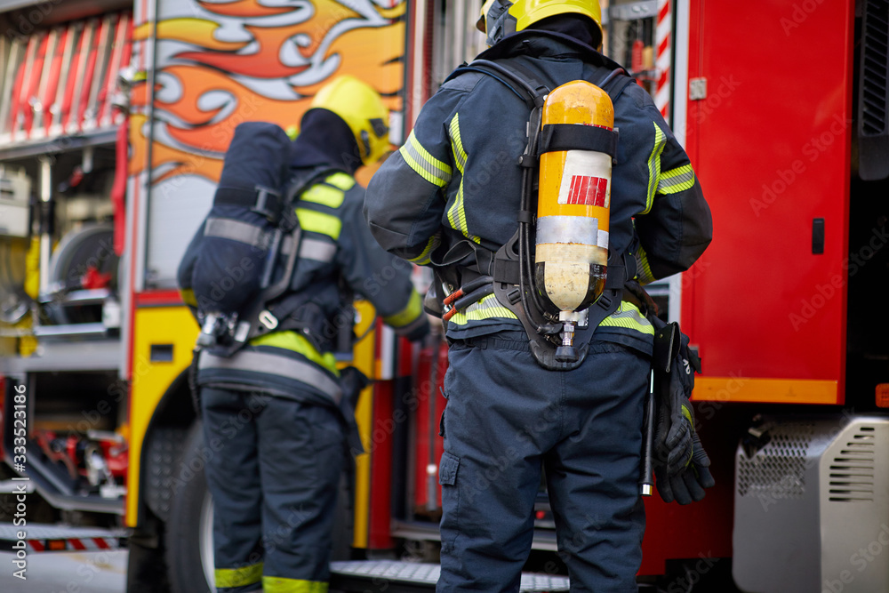 Fireman in uniform in front of fire truck going to rescue and protect. Emergancy servise concept. Fireman in uniform in front of fire truck going to rescue and protect. Emergancy servise concept.