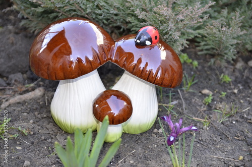 
Spring. Landscape. In the garden, among fresh green plants, decorative mushrooms stand.