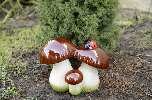 
Spring. Landscape. In the garden, among fresh green plants, decorative mushrooms stand.