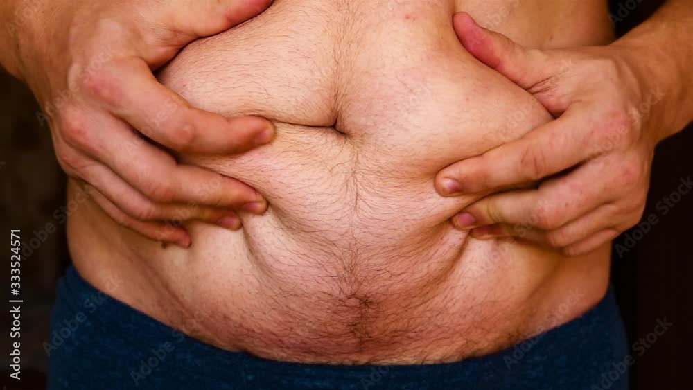 Overweight man shows his fat on his stomach and pats his stomach. Overweight man shows his fat on his stomach and pats his stomach.