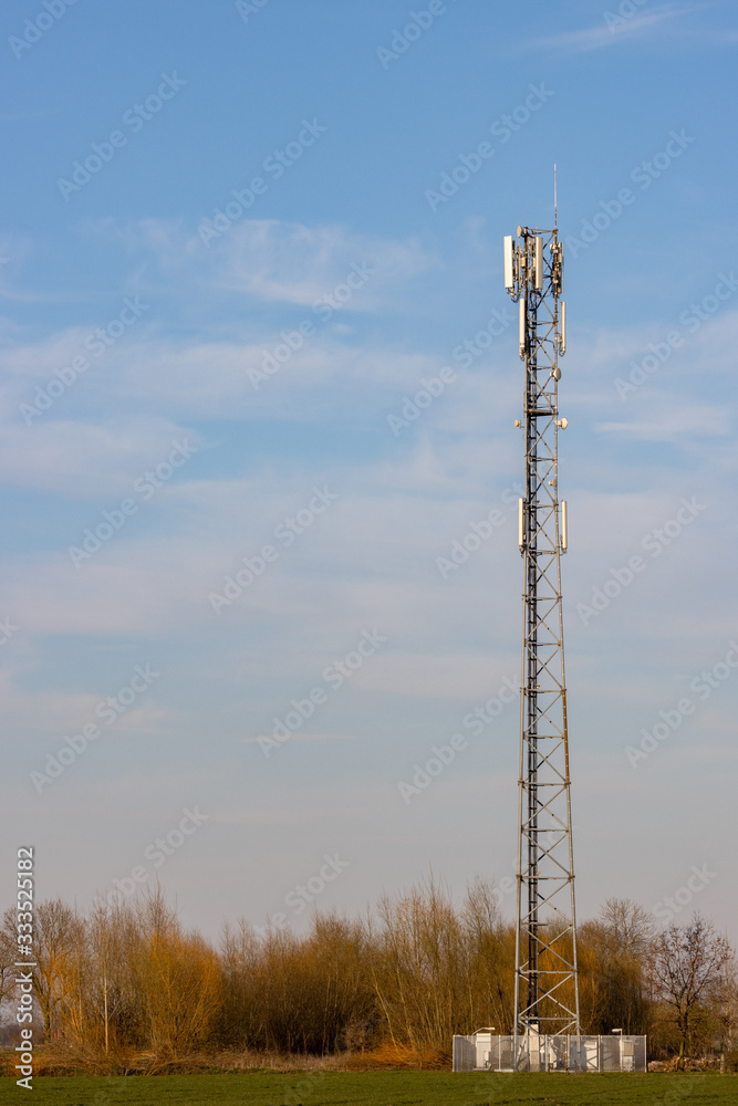 Cell phone tower in rural setting with blue sky in background Cell phone tower in rural setting with blue sky in background