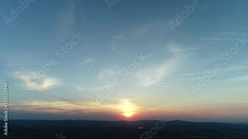 Red orange sunset cloudscape over blue evening sky with mountains silhouette on the horizon.