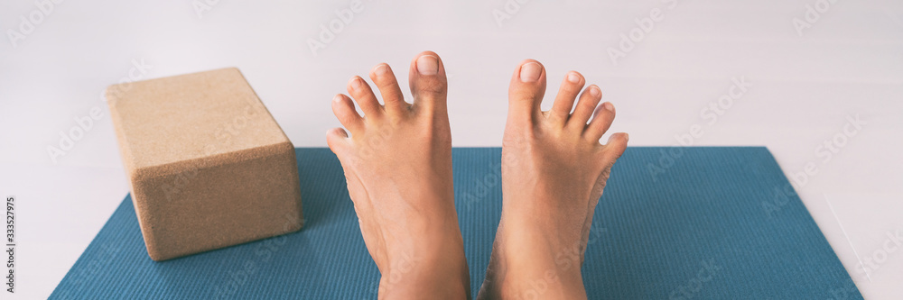 Yoga woman stretching feet spreading her toes doing toe stretch on exercise  mat of living room floor at home. Foot exercises stretches fun. Stock Photo