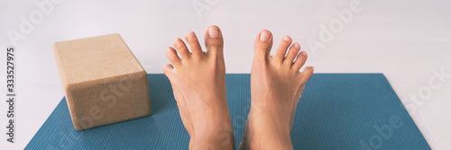 Yoga woman stretching feet spreading her toes doing toe stretch on exercise mat of living room floor at home. Foot exercises stretches fun.