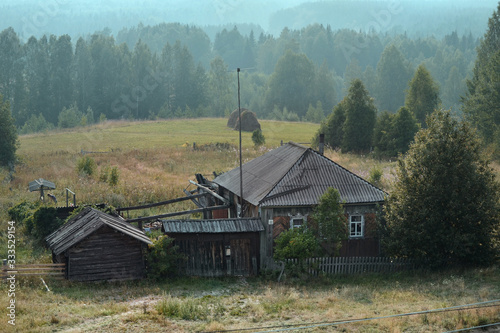 Russian village in the rays of the warm summer sun. Old wooden houses, fields and copses.