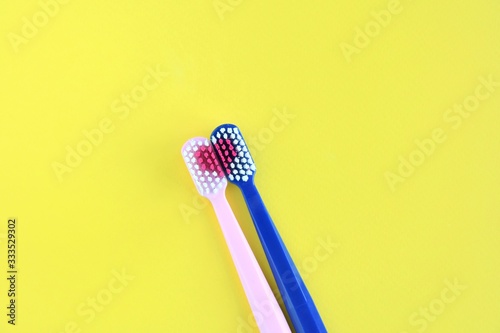 Two toothbrush for personal dental care on yellow background. Romantic toothbrushes with red heart. St. Valentine s Day concept. Lovers toothbrushes. Personal hygiene 