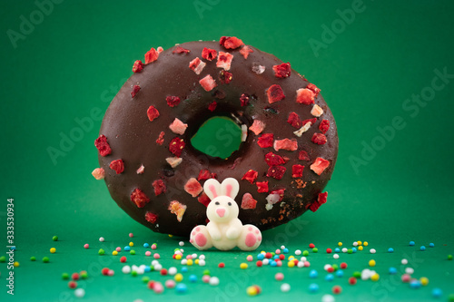 happy colored donut and sprinkles with bunny on green background