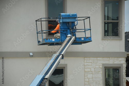 A construction worker working using boom lift vehicle on day time during corona pandemic in apartment complex at San Antonio Texas, concerning fact people are exposed no safety no quarantine isolation