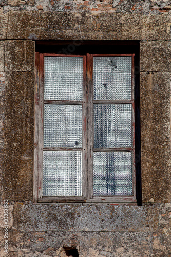 Antigua ventana de de madera vieja con cristales trasl  cidos y pared de piedra