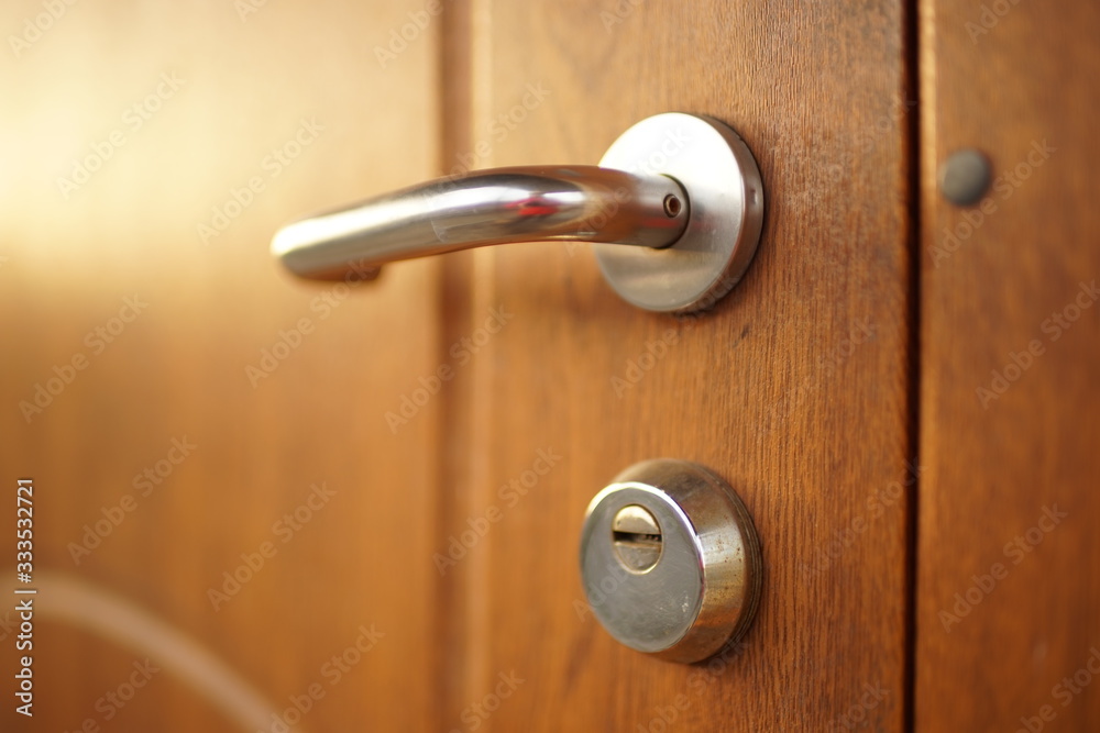 Shiny brown wooden door with chrome handle and keyhole Shiny brown wooden door with chrome handle and keyhole
