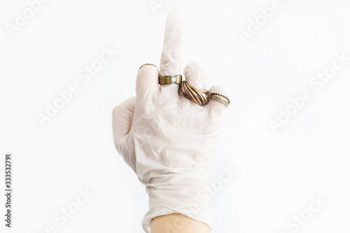 Hand showing middle finger in white medical glove with luxury ring on white background. Fuck off sign to coronavirus. Fashion in virus epidemic. Skin protection, prevention from virus in style.