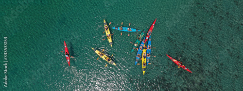 Aerial drone ultra wide photo of young athlete team practising sport canoe in tropical exotic bay with emerald sea