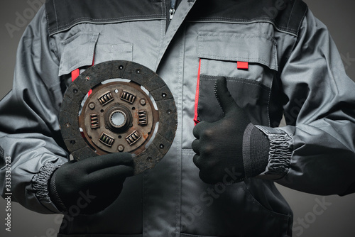 A car mechanic is showing an old car clutch disk close up. photo
