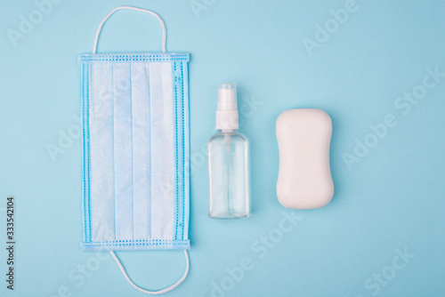 Novel corona virus fighting prevention concept. Top above overhead close up view photo of face mask bottle with spray and bar of white soap isolated over blue background