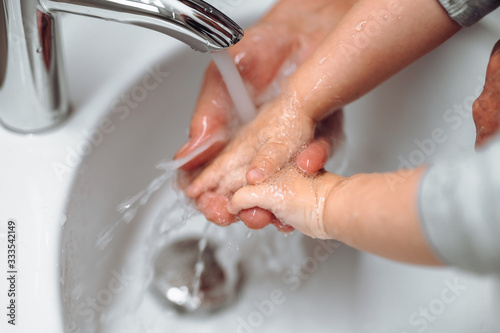 caucasian woman washing little baby boys hands. Hygiene and disinfection of hands at home with soap and tap water