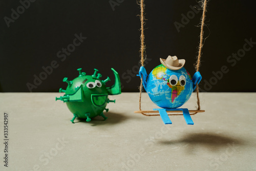 Green virus catching a toy earth on a swing