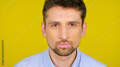 Close up confident bearded man on a yellow background with a place for text looks at the camera