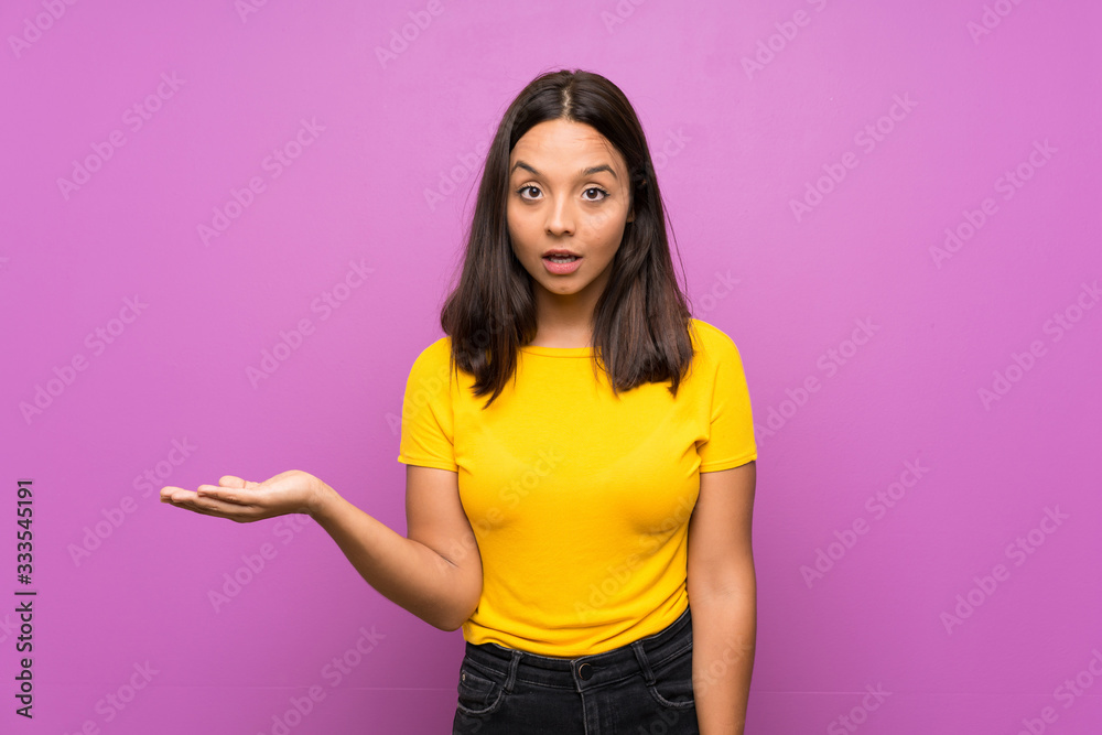 Young brunette girl over isolated background making doubts gesture Young brunette girl over isolated background making doubts gesture