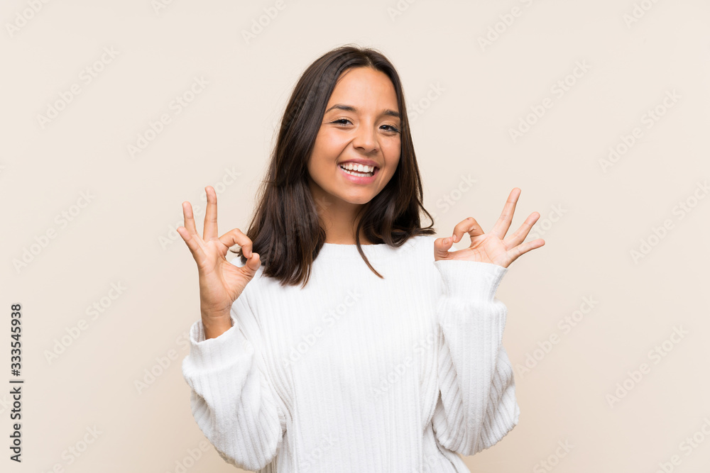 Young brunette woman with white sweater over isolated background showing an ok sign with fingers Young brunette woman with white sweater over isolated background showing an ok sign with fingers