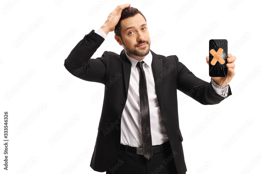 Sad businessman holding a broken mobile phone with plasters on the screen Sad businessman holding a broken mobile phone with plasters on the screen
