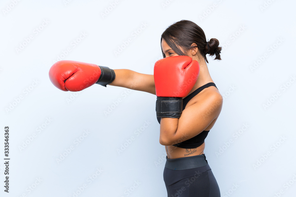 Young sport girl with boxing gloves over isolated blue background Young sport girl with boxing gloves over isolated blue background