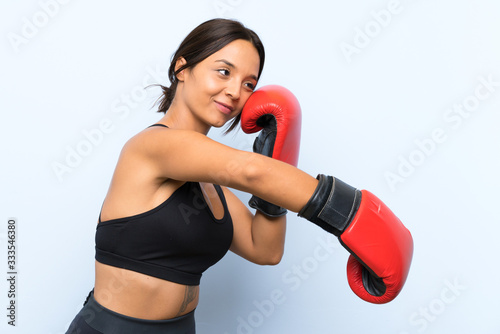 Young sport girl with boxing gloves over isolated blue background