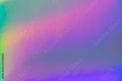 Abstract trendy rainbow holographic background in 80s style. Blurred texture in violet, pink and mint bright neon colors.