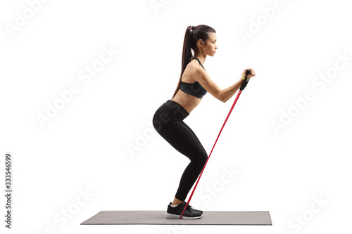 Full length profile shot of a young woman in sportswear exercising with a resistance band photo