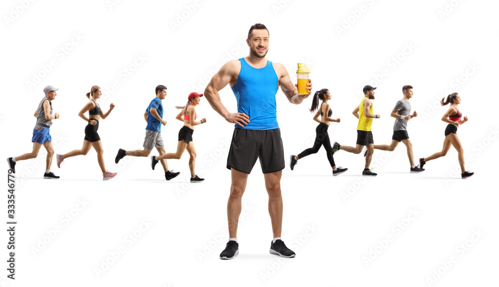 Fit young man holding a protein shake and people running in the back Fit young man holding a protein shake and people running in the back
