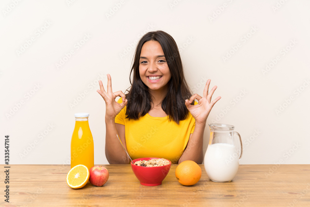 Young brunette girl having breakfast milk showing an ok sign with fingers Young brunette girl having breakfast milk showing an ok sign with fingers