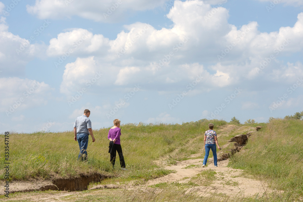 People are walking along country road on mild hill slope. People are walking along country road on mild hill slope.