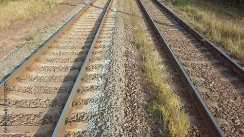 Aerial top view of empty train rails covered by forest camera tilt up