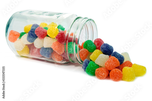 Colorful old fashioned spiced gumdrops spilling from a glass jar. Isolated.