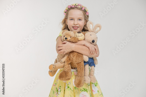 Girl holding bear and bunny with heart. White background