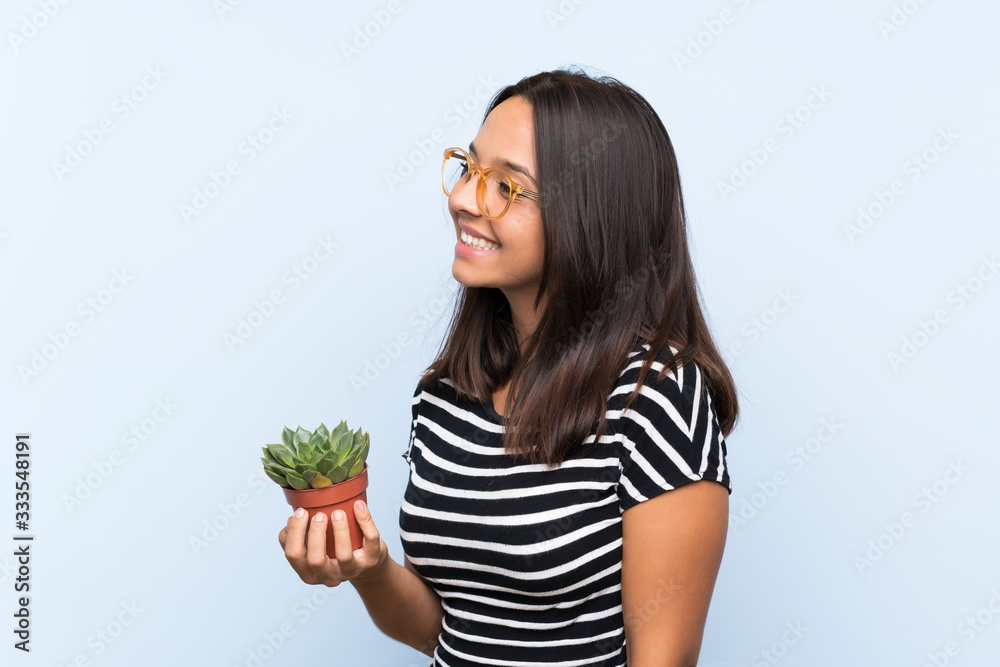 Young brunette woman holding a plant looking side Young brunette woman holding a plant looking side