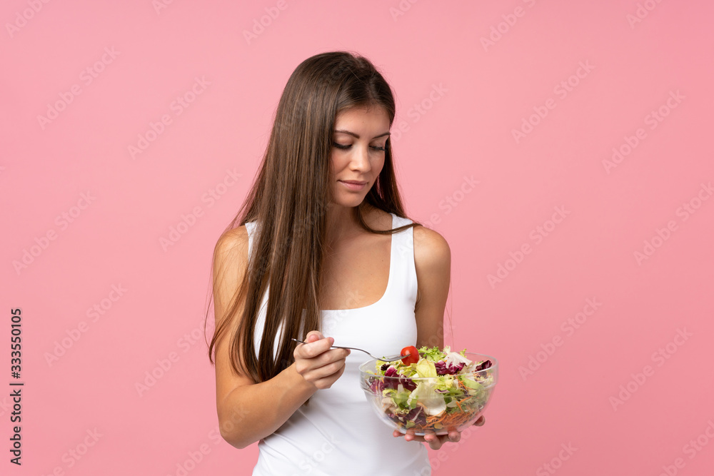 Young woman with salad over isolated pink wall Young woman with salad over isolated pink wall