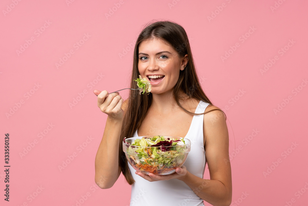 Young woman with salad over isolated pink wall