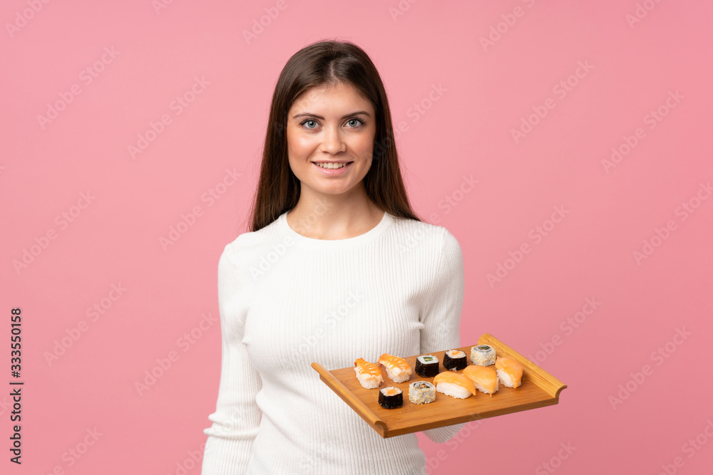 Young girl with sushi over isolated pink background smiling a lot Young girl with sushi over isolated pink background smiling a lot