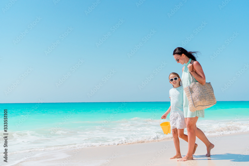 Little adorable girl and young mother at tropical beach