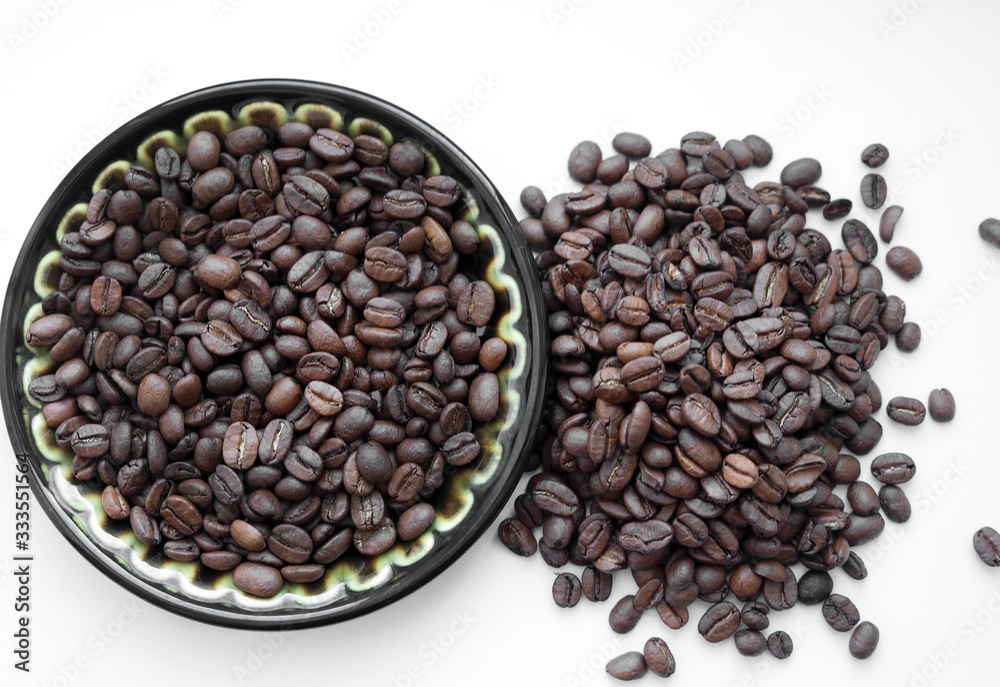 Fototapeta premium Natural coffee beans on a plate, nk white background. View from above.
